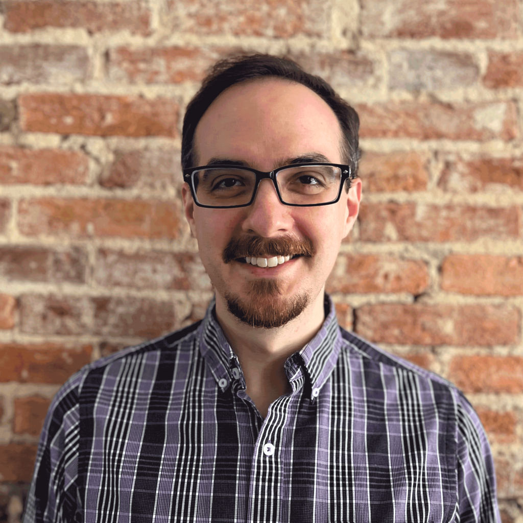 Eric Null is the Director of the Privacy & Data Project at CDT. Eric has rectangular glasses on and a striped shirt, while standing in front of a brick wall.