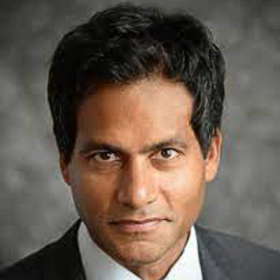 Jameel Jaffer. Knight First Amendment Institute. Wearing a white collared shirt and a dark grey suit, in front of a grey backdrop.