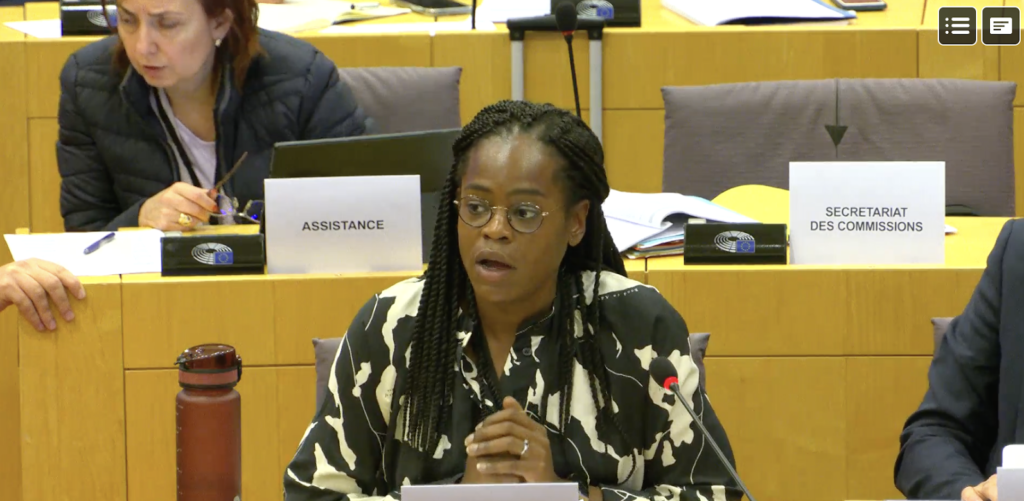 On 11 July, CDT Europe’s Asha Allen joined a hearing held by the Committee on Internal Market and Consumer Protection (IMCO) at the European Parliament. Asha is wearing a patterned shirt and glasses, speaking in front of a microphone.