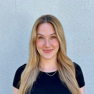 CDT Fellow Danielle Dougall, wearing a dark shirt in front of a light blue wall. Smiling, with light-colored hair.