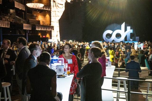 Guests at CDT's 2022 Tech Prom mix and mingle, with the main stage looming behind them.