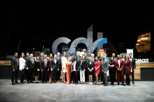 CDT staff picture, in front of the main stage at the Anthem. Large CDT logo on stage in background.
