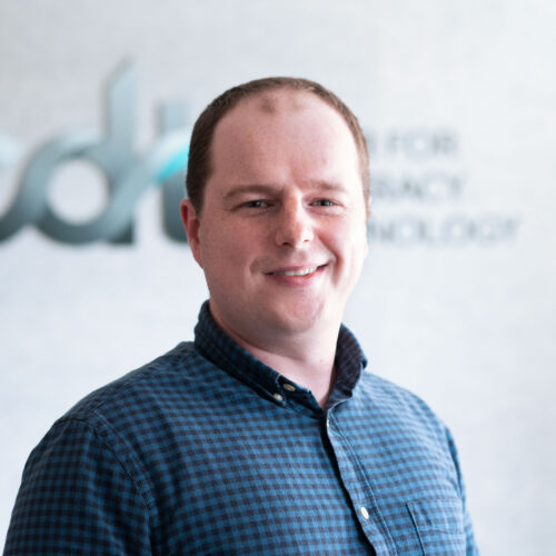 Jacob Kauffman, smiling and wearing a patterned collared shirt in front of the CDT logo.