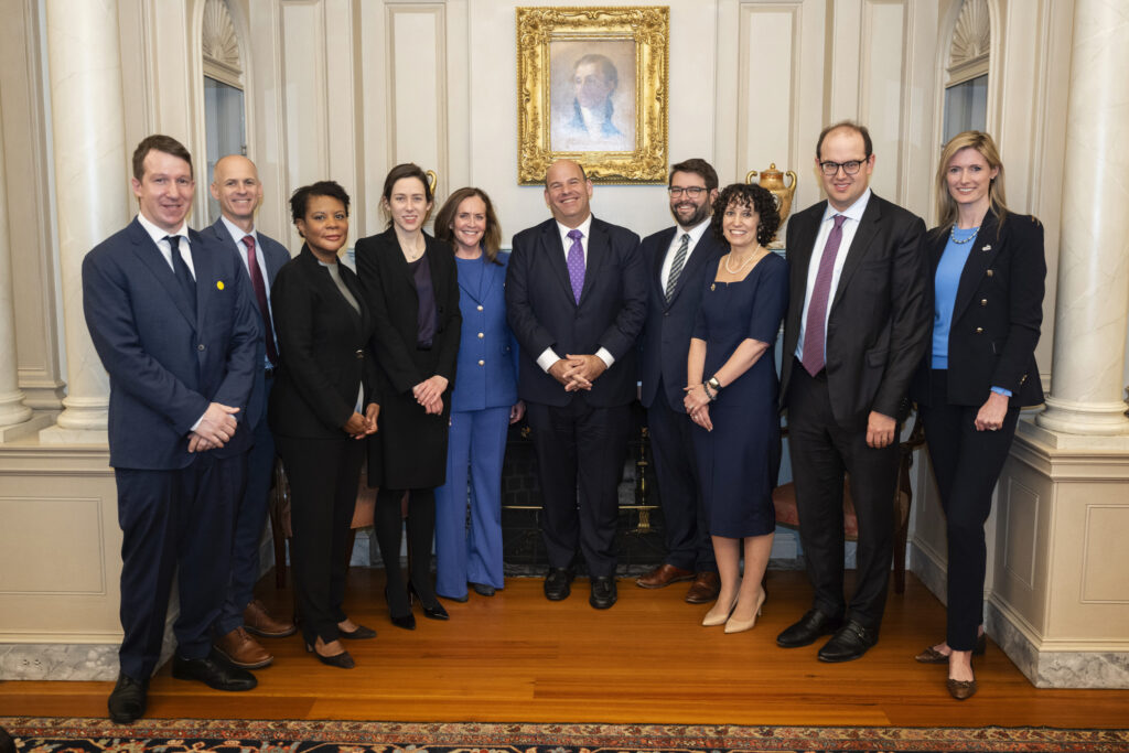 Photo shared with permission from Alexandra Givens. Givens stands alongside other speakers at the U.S. Department of State, in front of a framed painting.