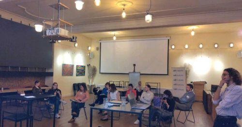 Participants of a June 2024 CDT Europe closed civil society workshop, discussing the advancement of fundamental rights in the AI Act implementation. Participants in chairs and around tables in discussion.