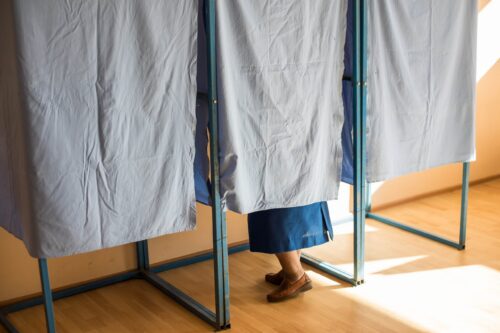 Color image of an unidentifiable person voting in a booth at a polling station, during elections.