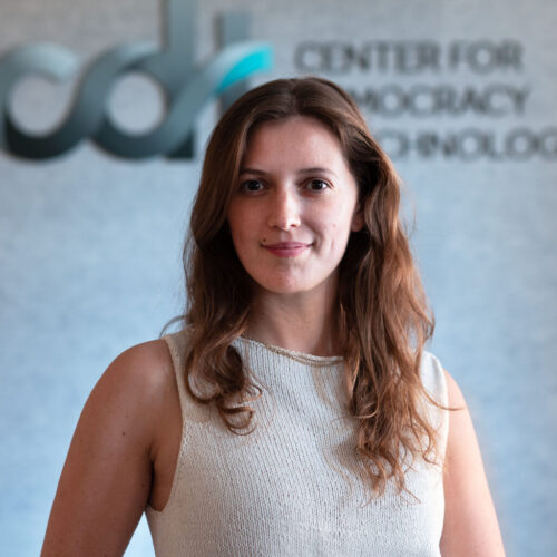 Isabel Linzer, smiling wearing a light colored knit top and necklace in front of a CDT logo.