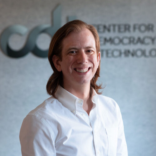 Drew Courtney, smiling in a white collared shirt in front of the CDT logo.