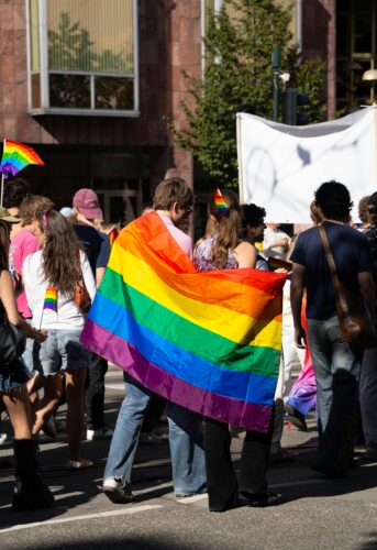 Woman wrapped in pride flag at protest.