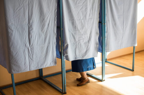 Color image of an unidentifiable person voting in booths at a polling station, during elections.