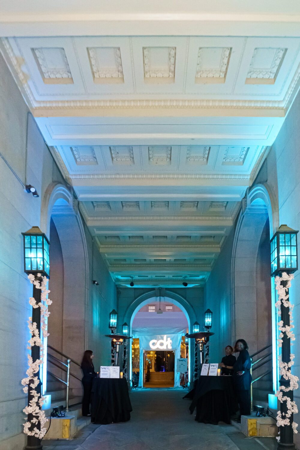Exterior of the 2025 Spring Fling. Stone columns surrounding a hallway lit with blue lights.