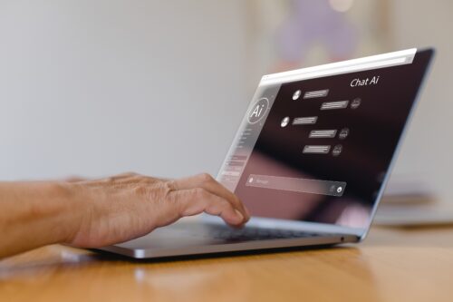 Person typing on laptop screen that says AI.